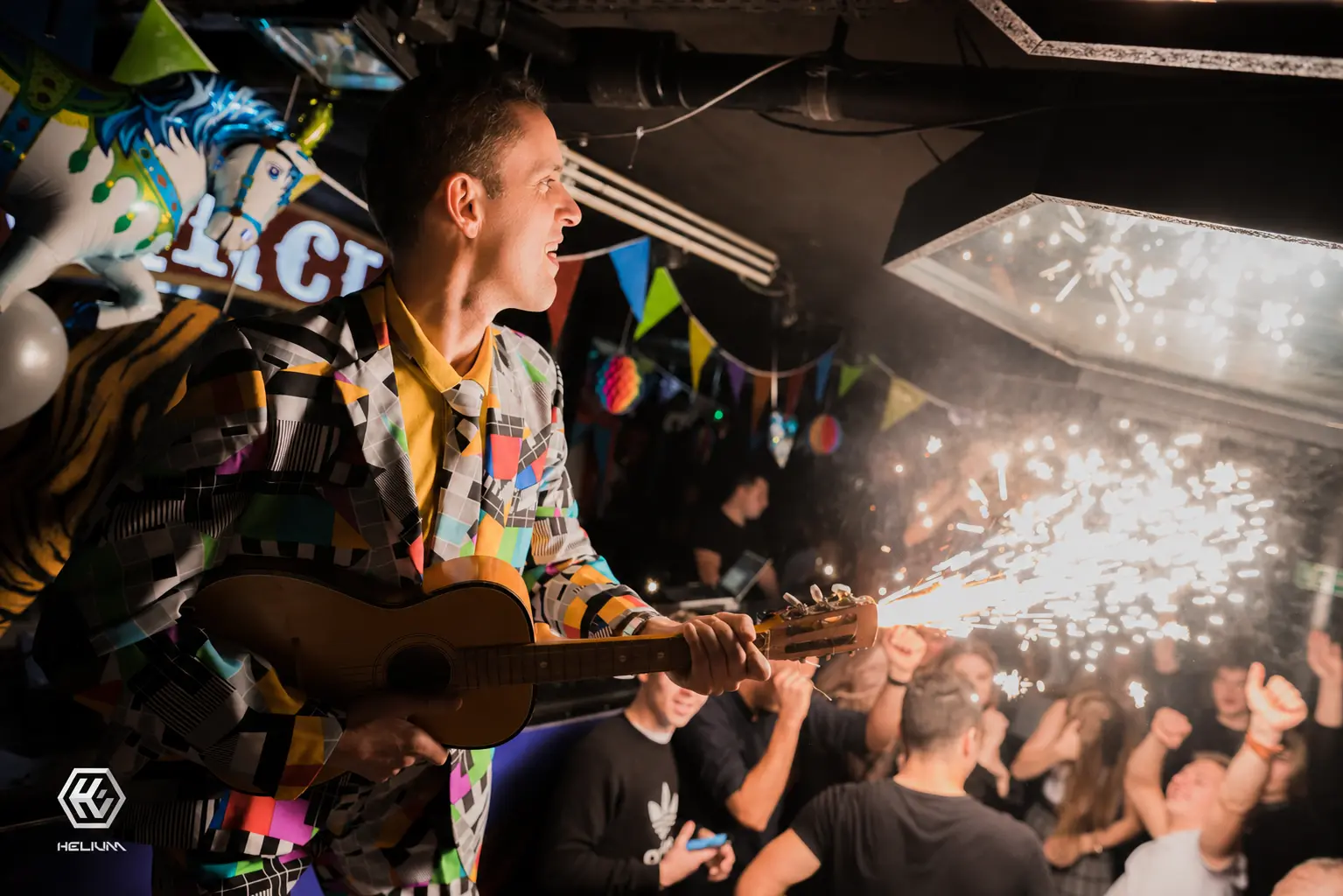 Bogdan Michalec – showman na event z pirotechniką sceniczną Bogdan Michalec jako showman gra na gitarze z pirotechniką sceniczną przed dorosłą publicznością.